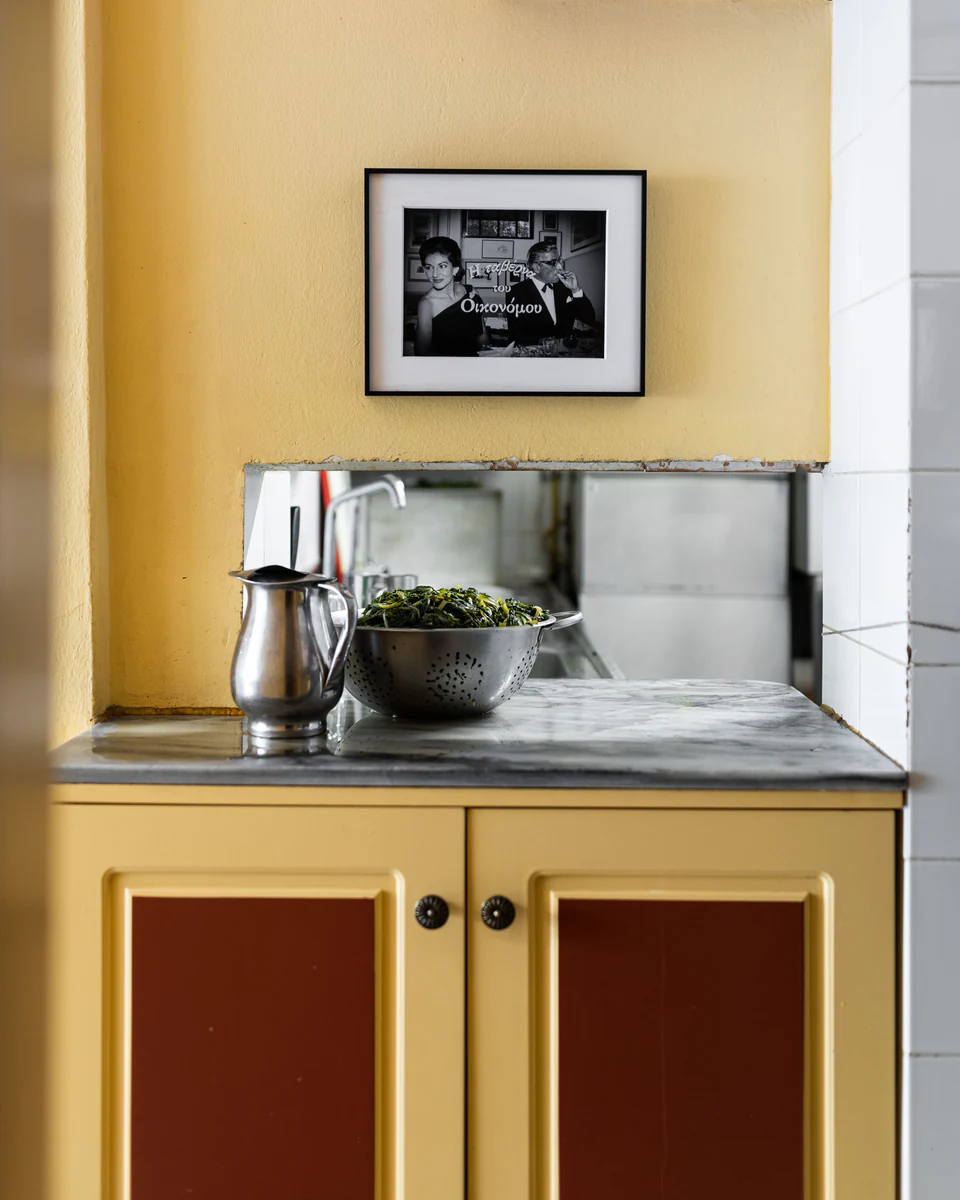 A yellow kitchen cabinet and a framed photograph